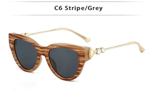 Détail de lunettes de soleil œil-de-chat avec monture rayée et branches dorées à strass