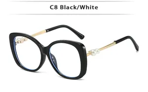 Detail of cat-eye sunglasses featuring golden temples and decorative white pearls