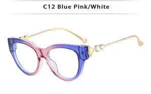 Détail de lunettes œil de chat dégradé bleu-rose avec branche dorée ornée d'un cœur strass