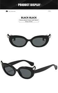 Detail view of black cat eye sunglasses with devil horn design and sparkling rhinestones