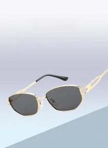 Detail of gold metal frame sunglasses with polygon geometry and deep grey lenses