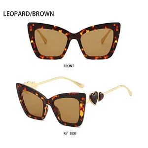 Detail van luipaard cat-eye zonnebril met gouden pootjes en hartvormige accenten