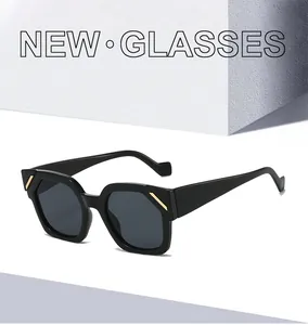 Détail de lunettes de soleil noires à monture épaisse avec accents dorés sur fond blanc