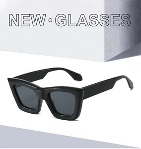 Detail of trendy black square frame sunglasses with dark lenses on a white platform
