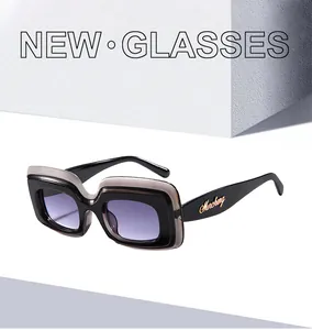 Détail de lunettes de soleil carrées avec monture bicolore et logo doré sur la branche