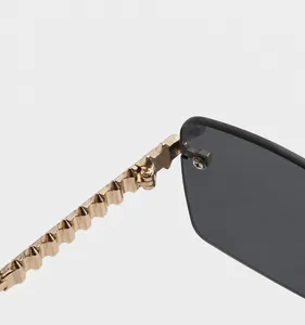 Detalle de patillas de metal dorado con textura geométrica y bisagras para gafas de sol