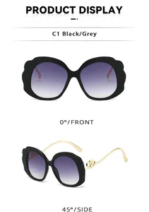 Detail view of oval sunglasses with gold double heart metal accents and gradient lenses