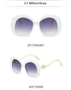 Detail view of oval white sunglasses with wavy frames and golden heart temple accents