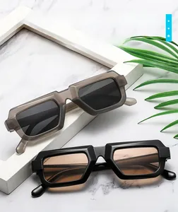 Gros plan de lunettes de soleil rectangulaires rétro en gris et noir sur marbre