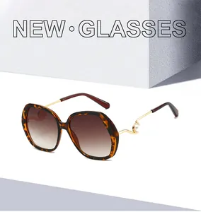 Detail of tortoise shell sunglasses featuring gold curved temples and pearl accents