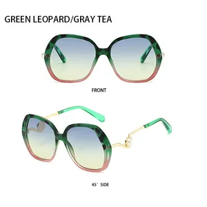 Detail view of large frame sunglasses with green leopard pattern and gold pearl temple