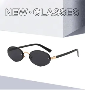 Close-up of rimless oval sunglasses featuring gold metal bridge and dark tinted lenses