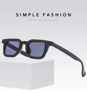 Close-up of black rectangular sunglasses with grey lenses on a white pedestal
