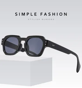 Close-up of thick black square sunglasses featuring classic double metal rivets on corners