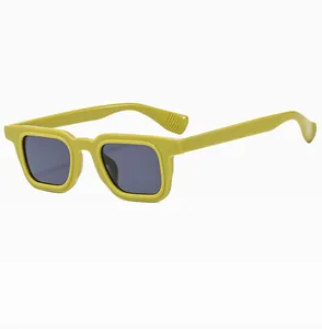 Detail showing the heavy mustard yellow square frame and dark gray lenses of the sunglasses