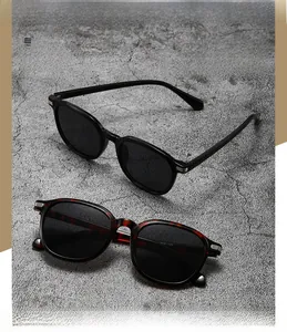 Close-up of black and tortoiseshell oval sunglasses with polarized lenses on grey concrete