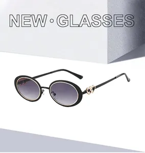 Detail of oval sunglasses featuring purple gradient lenses and gold dual heart hinges