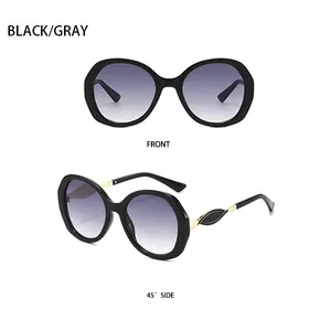 Details der ovalen schwarzen Sonnenbrille mit Goldakzenten und grauen Verlaufsgläsern