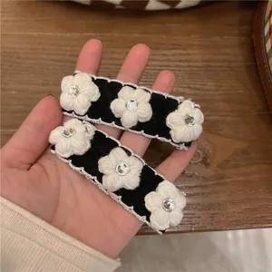 Set of two black camellia hair clips with white lace edges and sparkling rhinestones
