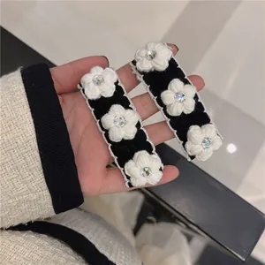 Pair of knitted camellia hair clips with white yarn flowers and sparkling rhinestones