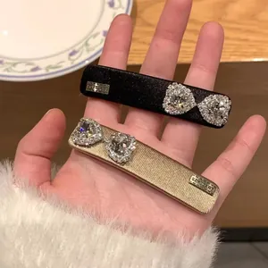 Close-up of sparkling heart rhinestone bow hair clips with Love Days metal plate