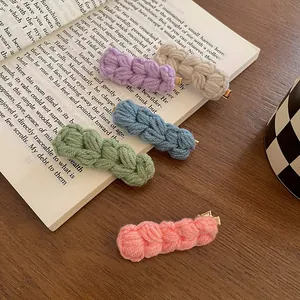 5-delige set gebreide wollen haarspelden in diverse kleuren op een geopend vintage boek