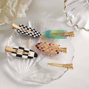 Lot de 5 barrettes à cheveux à motifs damier et marbre sur un plateau décoratif
