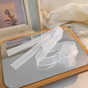 Elegant white lace choker with a camellia flower pendant and bow on a mirror tray