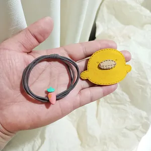 Cute cartoon hair ties featuring a pink carrot charm and a yellow duck felt accessory