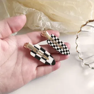 Gros plan de pinces à cheveux à damier noir et blanc avec des attaches en métal doré
