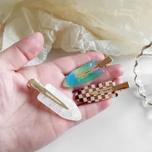Lot de barrettes à motif damier et marbre avec base en métal doré tenues en main