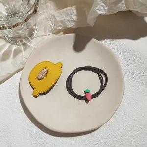 Cute lemon fabric hair clip and carrot pendant elastic hair tie set on a ceramic dish