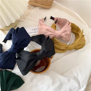 Detail view of colorful satin bow headbands in navy, pink, yellow, and green fabric