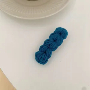 Detail van een grof gebreide wollen haarclip in diepblauw met gevlochten textuur