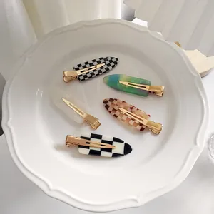 Détail de cinq barrettes à damier et motifs marbrés posées sur une assiette en céramique