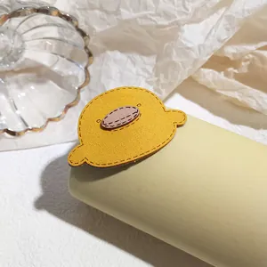 Detailed view of yellow cartoon bird hair tie with fine stitching and soft texture