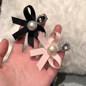 Pink and black ribbon bow hair clips with faux pearls and rhinestones on plush background