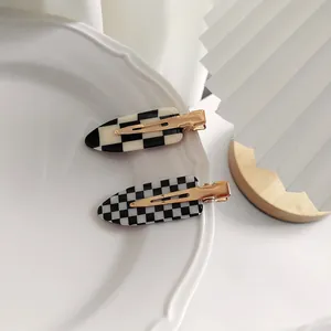 Détail de pinces à cheveux à damier sur un plateau blanc aux accents dorés élégants