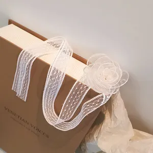 Detail of white lace choker featuring a delicate mesh camellia flower on a vintage book