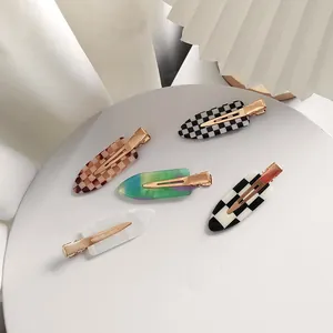 Vue détaillée de cinq pinces à cheveux sans trace aux motifs damier et marbre avec base dorée