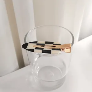 Gros plan sur la pince à cheveux à damier noir et blanc avec base en métal doré