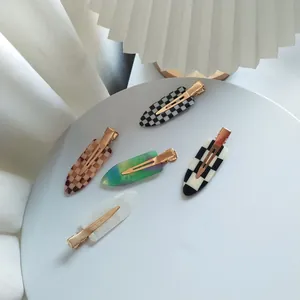 Détail de cinq barrettes à motif damier et marbré avec pinces croco en métal doré