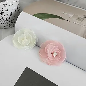 Detailed view of layered chiffon camellia hair clips in soft pink and white tones