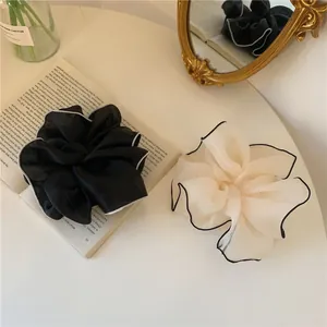 Détail de chouchous en tulle oversize noir et beige avec bords contrastés sur un bureau