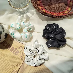 Three-piece satin scrunchies in black, white and beige with minimalist smiley face prints