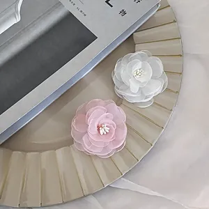 Detail of handmade pink and white camellia hair clips with layered organza petals and beads
