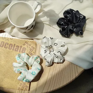 Close-up of three satin scrunchies with smiley faces on a rustic wooden table