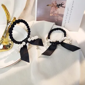 Détail du nœud noir élégant et des perles blanches sur des chouchous pour femmes