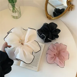 Détail de chouchous en organza transparent avec bordure contrastée en beige, noir et rose