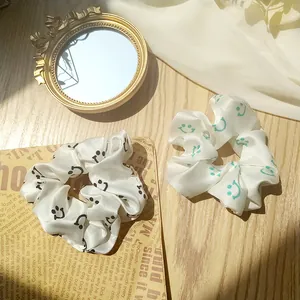 Close-up of two satin scrunchies with smiley faces on a rustic wooden background